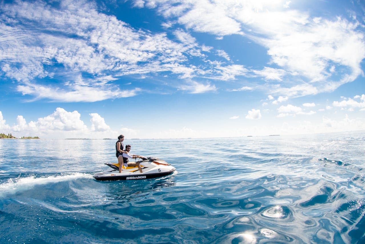 Dos personas navegando en moto de agua sobre aguas turquesas